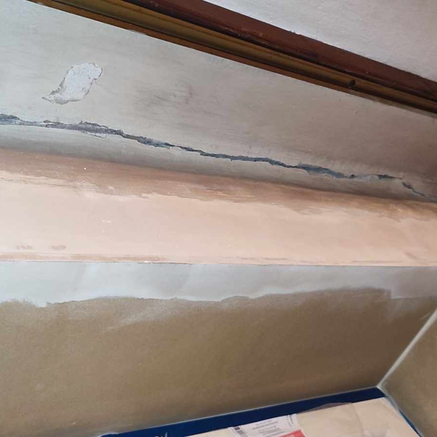 Pęknięcie na suficie przed nałożeniem gładzi, widoczny fragment listwy przysufitowej i zabezpieczenia folią malarską.