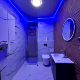 Nowoczesna łazienka z marmurowymi płytkami, podświetleniem LED i geometryczną ścianą akcentującą