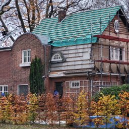 MULTI ENERGA SPÓŁKA Z OGRANICZONĄ ODPOWIEDZIALNOŚCIĄ - Dom w Poznaniu w trakcie prac dekarskich; widoczne rusztowania, częściowo zdjęte poszycie i nowa membrana dachowa w kolorze zielonym.