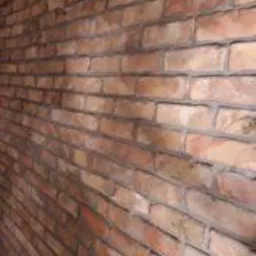 Ściana wykończona czerwoną cegłą klinkierową z widoczną fugą, ułożona pod kątem, tworząca wrażenie tunelu.