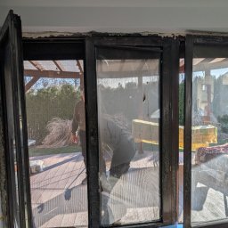 REC NOVA Wojciech Tomaszewski - Demontaż starej stolarki okiennej z uszkodzonymi szybami. Widoczne ślady pianki montażowej i przygotowania do instalacji nowych okien.