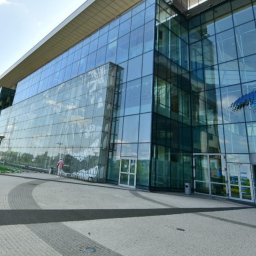 Phu - Nowoczesny, przeszklony budynek biurowy z widoczną osobą w oddali i dekoracyjnym wzorem na jednej ze szklanych ścian.