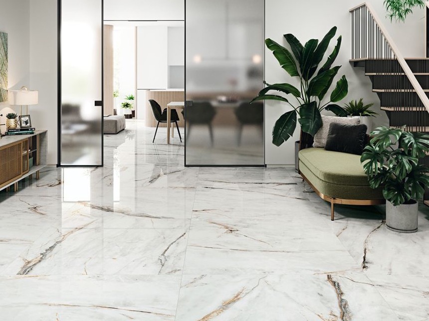 Błyszcząca podłoga z płytek imitujących marmur w nowoczesnym salonie z zieloną sofą i szklanymi drzwiami przesuwnymi.