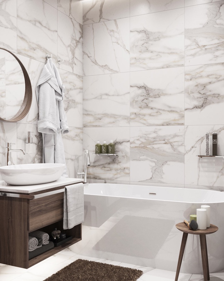 Nowoczesna łazienka z białymi płytkami imitującymi marmur, owalną umywalką na drewnianej szafce, białą wanną wolnostojącą i okrągłym lustrem z drewnianą ramą. Na ścianie zawieszony biały szlafrok...