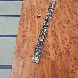 Usługi Remontowo Budowlane - Ułożone panele podłogowe o wzorze drewna, poziomica z zabrudzeniami oraz zwinięta miarka leżą na podłodze, widoczny fragment podkładu pod panele.