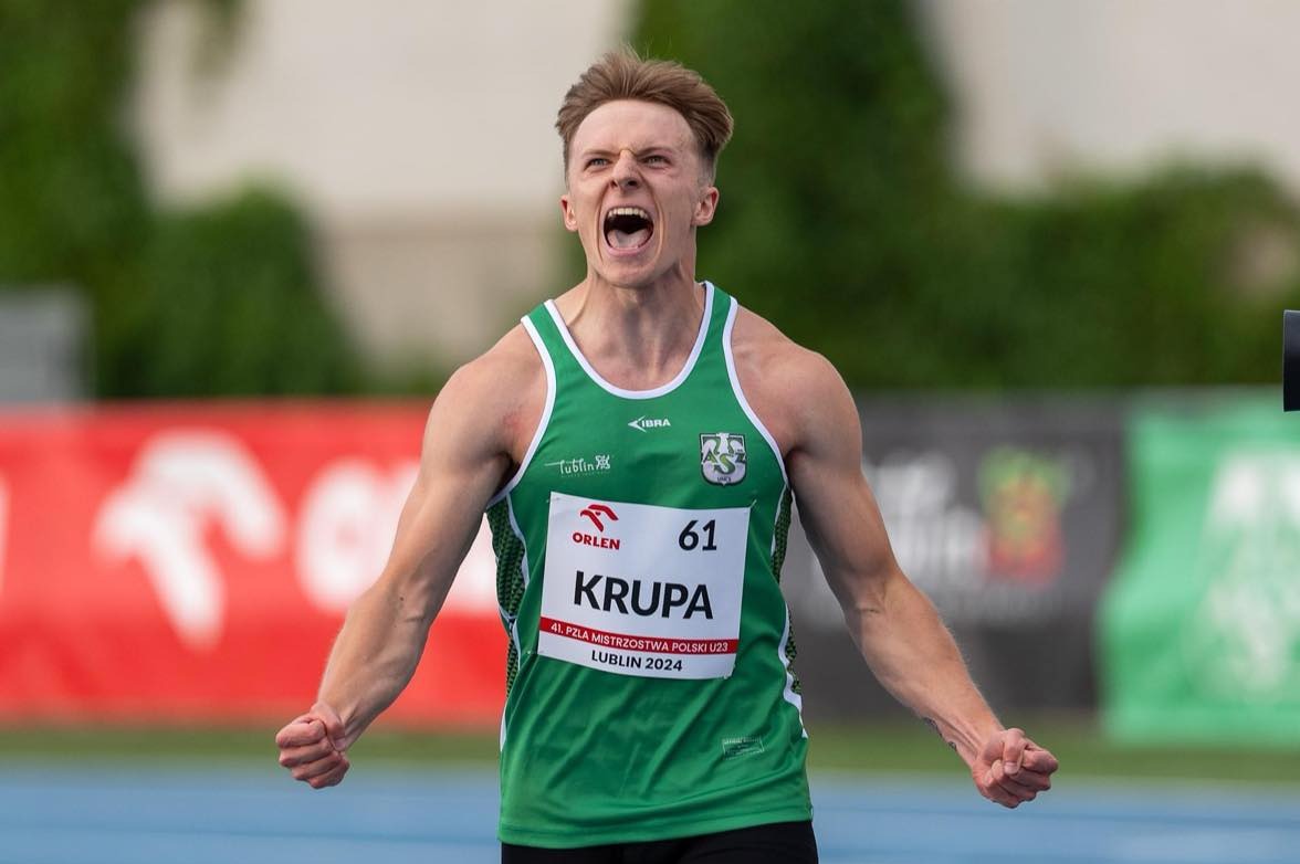 Młody sportowiec w zielonym stroju z numerem 61, krzyczący z radości po biegu na tle stadionu w Lublinie podczas 41. PZLA Mistrzostw Polski U23 w 2024 roku.