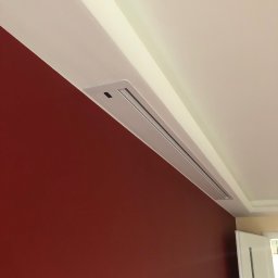 GRAB-TECH Aleksandra Grabowska - Szczegół wykończenia wnętrza: Czerwona ściana kontrastuje z białym sufitem, w którym zamontowany jest liniowy nawiewnik klimatyzacji.