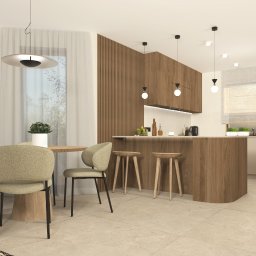 PRACOWNIA PROJEKTOWA MARZENA SZKUDLARZ - Jasne wnętrze kuchni z jadalnią, okrągły stół z czterema krzesłami w odcieniach beżu, wyspa kuchenna z drewnianym wykończeniem i trzema stołkami barowymi, duże okna z białymi zasłonami, nowoczesne...