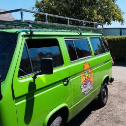 Jakub Przepiórka - Zielony bus VW z metalowym bagażnikiem dachowym na tle drzewa i nieba. Bagażnik wykonany ze spawanych, metalowych rurek.