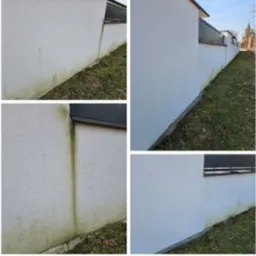 Fragment elewacji budynku z widocznymi zabrudzeniami i śladami porostu glonów, zarys dachu i fragment trawnika w tle.