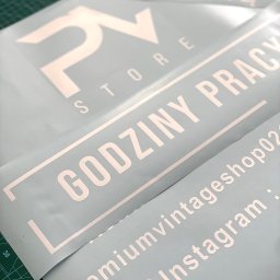 Magnetic design - Białe, wycięte napisy na niebieskiej folii, układające się w hasła reklamowe i dane kontaktowe, leżące na zielonej macie. Widoczne logo 'PV STORE' i adres Instagram.