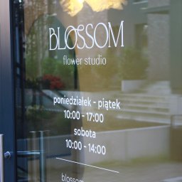 Magnetic design - Oklejona witryna kwiaciarni 'Blossom' w Szczecinie z godzinami otwarcia i adresem strony internetowej. Widoczne odbicia wnętrza i dekoracji.