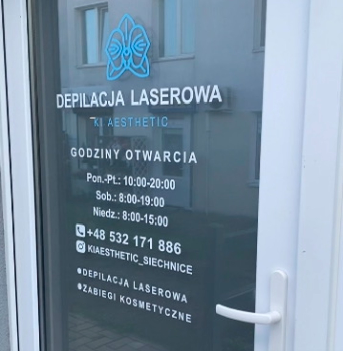 Szklane drzwi wejściowe z napisem 'Depilacja Laserowa' i logo, godziny otwarcia, numer telefonu i nazwa profilu na Instagramie.