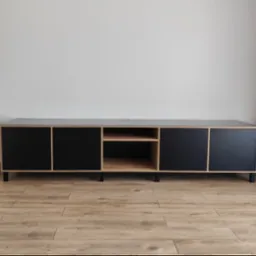 Nowoczesna szafka RTV z czarnymi frontami i drewnianymi elementami, stojąca na drewnianej podłodze, na tle szarej ściany i zasłony.