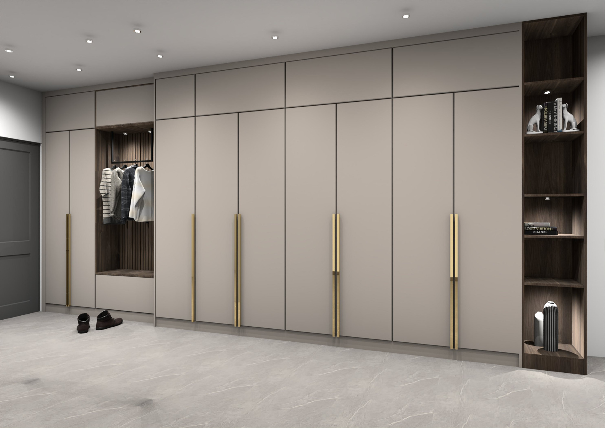 Beżowa szafa z długimi, złotymi uchwytami, otwartą wnęką z ubraniami na wieszakach i ciemnymi butami na podłodze, uzupełniona regałem z książkami i dekoracjami.