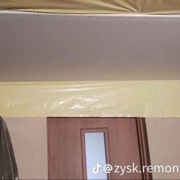 Zysk Remonty - Montaż płyty gipsowo-kartonowej na suficie, folia ochronna zabezpiecza ściany i meble podczas prac.