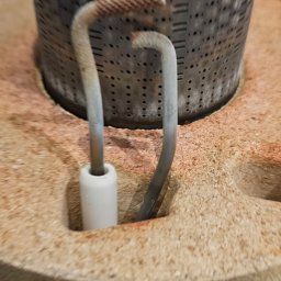 ZUH Broser - Detail pieca gazowego: palnik z elektrodami zapłonowymi, widoczne ślady użytkowania. Elementy pieca w zbliżeniu, ukazujące detale konstrukcyjne.