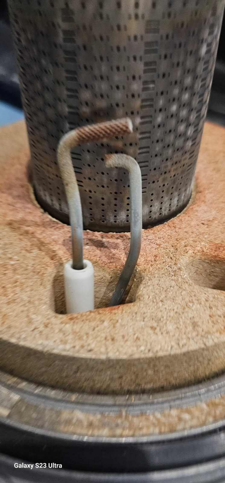 Detail pieca gazowego: palnik z elektrodami zapłonowymi, widoczne ślady użytkowania. Elementy pieca w zbliżeniu, ukazujące detale konstrukcyjne.