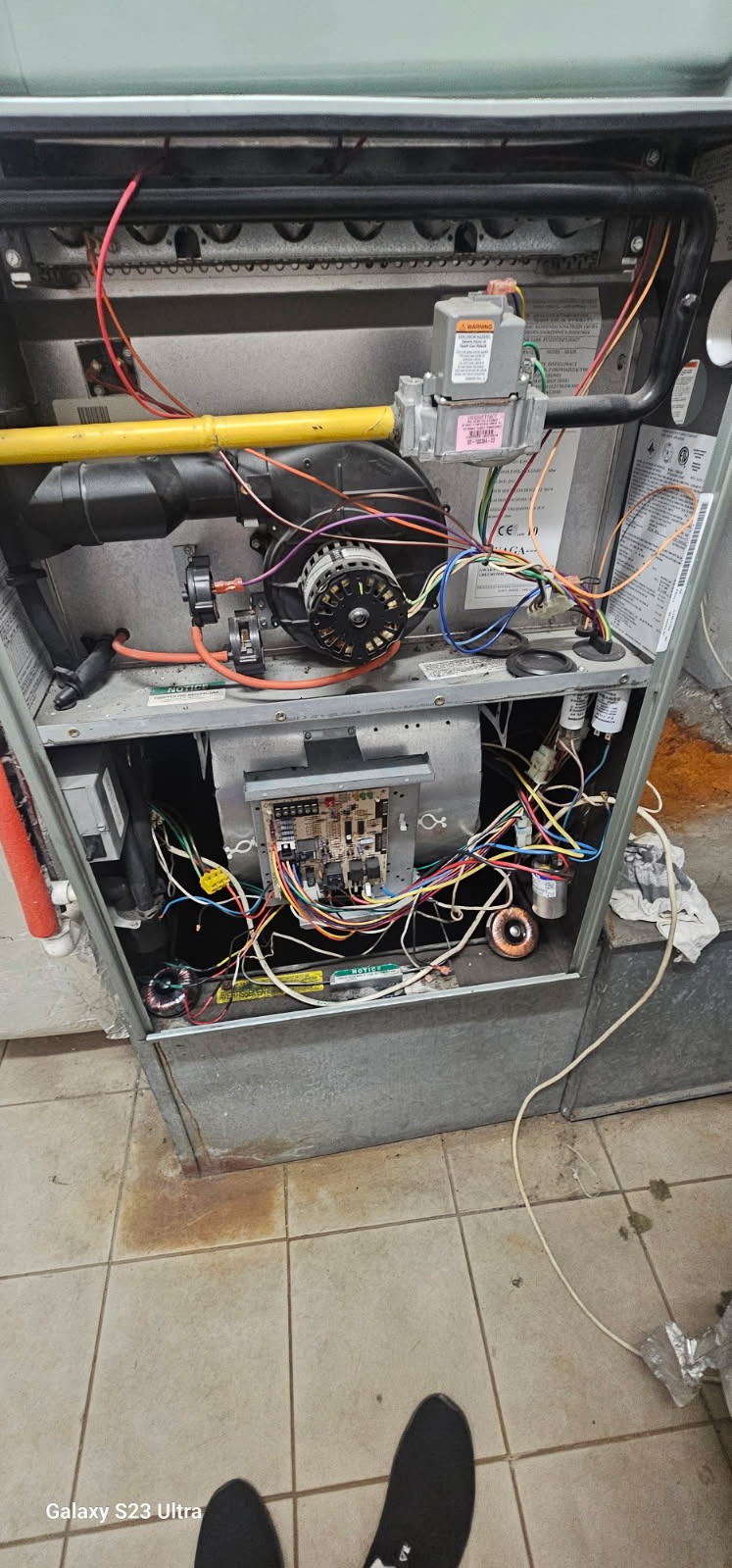 Otwarty piec gazowy z widocznymi elementami wewnętrznymi, w tym wentylatorem, przewodami i płytą sterującą. Widoczne ślady użytkowania i potencjalne zabrudzenia.