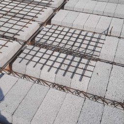 ZA&LE SP.Z.O.O - Wiązanie zbrojenia na stropie z szarego bloczka betonowego, widoczne fragmenty szalunku.