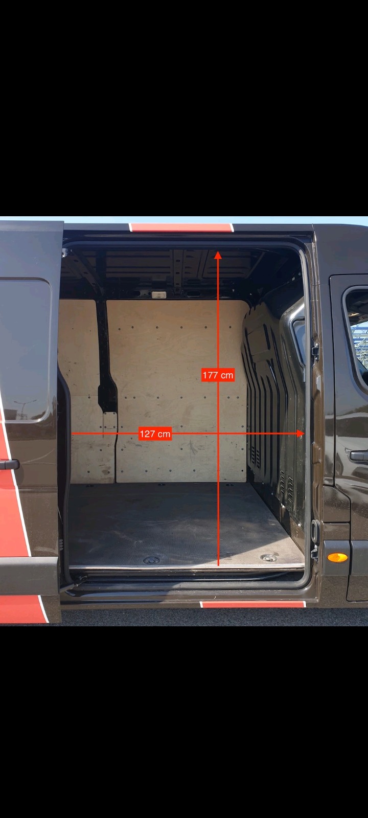 Wnętrze pustego, wyłożonego sklejką busa z otwartymi drzwiami bocznymi, z naniesionymi wymiarami 177 cm wysokości i 127 cm szerokości.