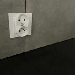 Podwójne, białe gniazdko elektryczne zamontowane na szarej, strukturalnej ścianie nad czarnym blatem. Widok z bliska, neutralne oświetlenie.