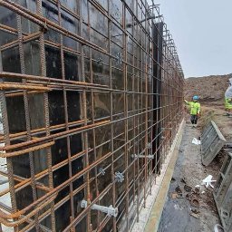 Płyty fundamentowe, wymiana gruntu, budowa domu - BUD-MAX - Szczegółowe ujęcie szalunku zbrojeniowego z widocznymi dystansami i elementami mocującymi, przygotowanego do zalania betonem na budowie w Krakowie.