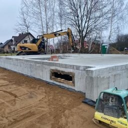 Płyty fundamentowe, wymiana gruntu, budowa domu - BUD-MAX - Wylany fundament z oknem piwnicznym w Tarnowie, widoczny żółty mini-koparka CAT oraz zagęszczarka gruntu AMMANN, przygotowany teren pod budowę domu.