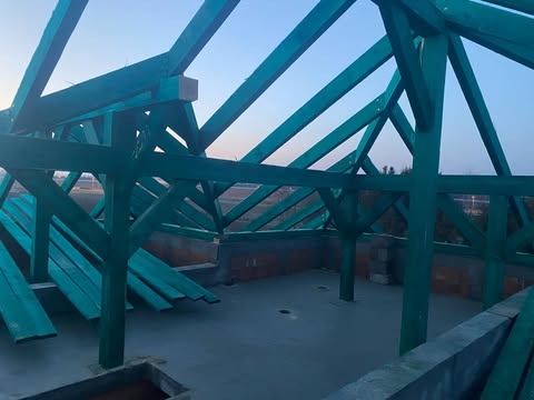 Konstrukcja więźby dachowej z impregnowanego drewna w kolorze zielonym, widok z wnętrza budowanego domu jednorodzinnego, ściany z bloczków betonowych.