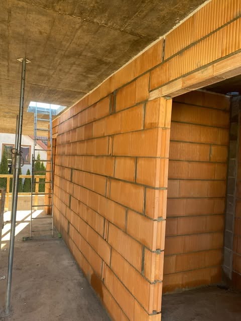 Budowa domu jednorodzinnego w Bogumiłowicach: murowane ściany z pustaków ceramicznych Porotherm, widoczne zbrojenia, betonowy strop i stalowe podpory szalunkowe, etap SSO.