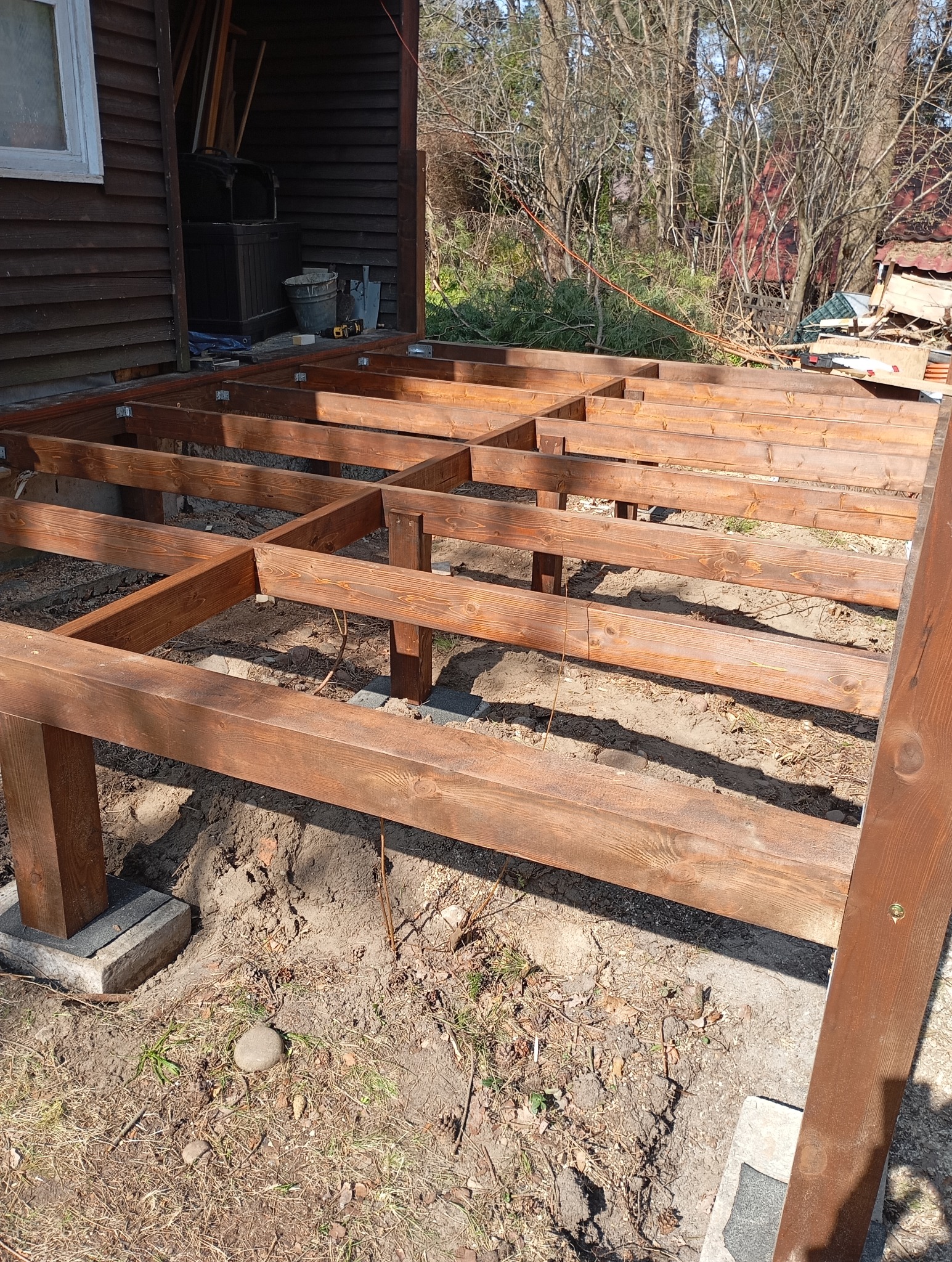 Konstrukcja nośna z belek drewnianych na betonowych bloczkach, przygotowywana pod budowę tarasu, widok z boku.