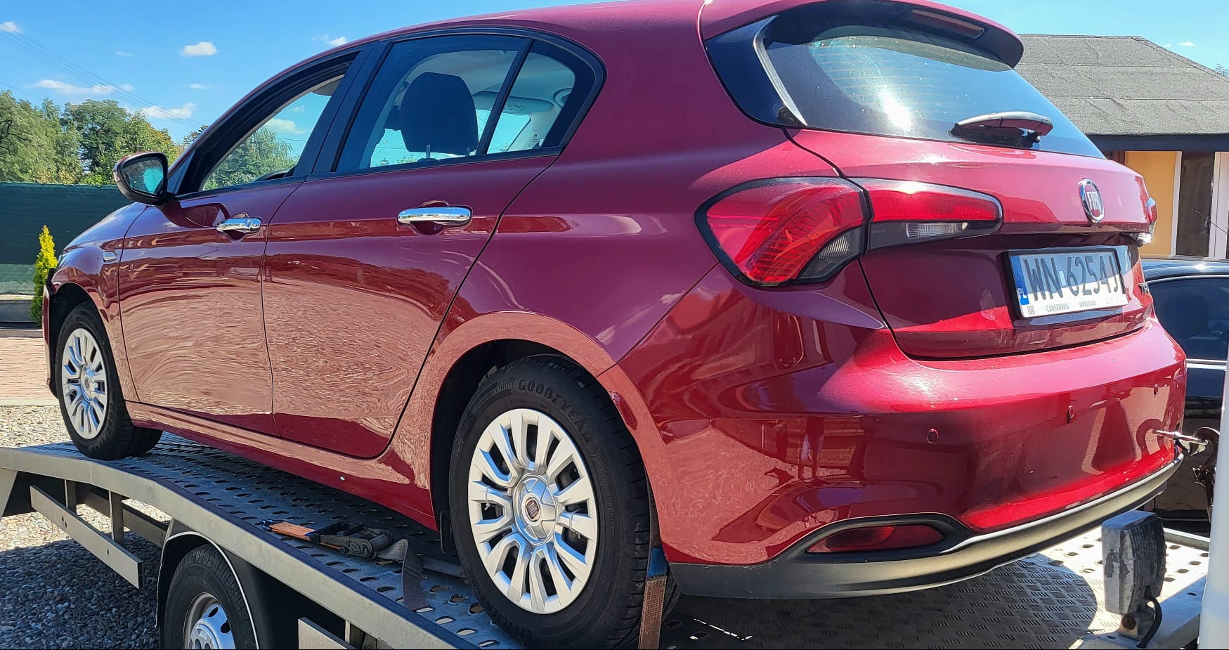Czerwony Fiat Tipo na lawecie w Warszawie, widok z tyłu, tablica rejestracyjna WN 6254J, zabezpieczony pasami transportowymi.