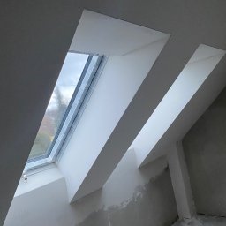 Nikon Construction Heorhii Nikonenko - Wykończone wnęki okienne na poddaszu ze świeżo pomalowanymi ścianami, widoczne ślady po szpachlowaniu. Okno dachowe z widokiem na zewnątrz.