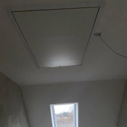 Nikon Construction Heorhii Nikonenko - Wykończone poddasze z oknem dachowym i klapą rewizyjną w suficie. Ściany przygotowane do malowania, widoczne gładzie. Minimalistyczny design.