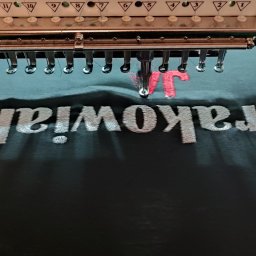 Koszulka w trakcie haftowania. Maszyna 15-sto igłowa, pozwalająca na haft do nawet 15 kolorów nici na jednej grafice bez potrzeby zmiany.