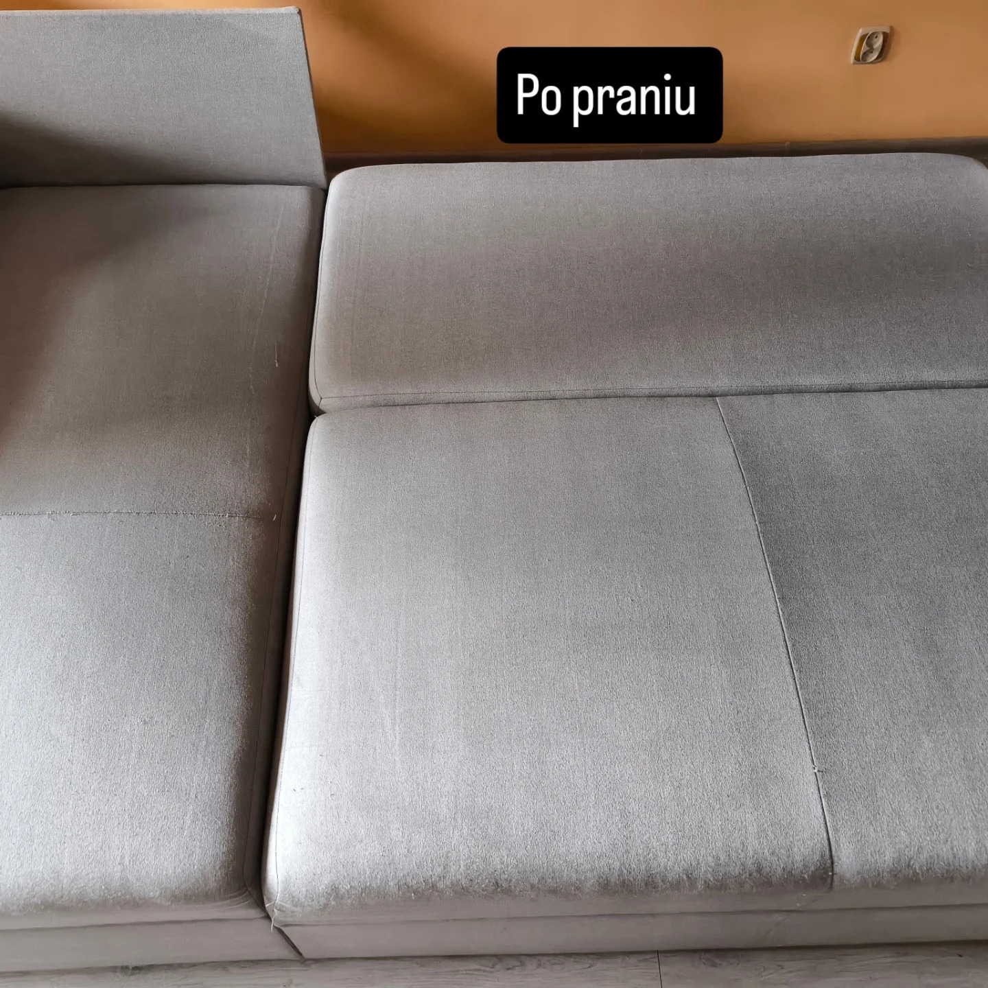 Szara, rozłożona sofa po czyszczeniu, widoczne różnice w odcieniach na poszczególnych segmentach. Tekst 'Po praniu' w górnej części kadru.