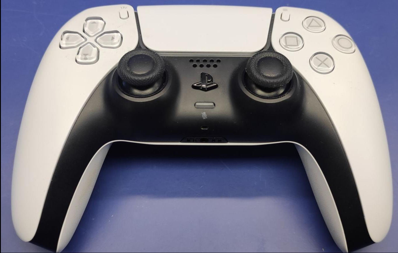 Biało-czarny kontroler do gier wideo leży na niebieskim tle, widoczne przyciski, analogi i logo.