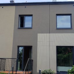 PrimeHome Oleksandr Prydvornyi - Nowoczesny dom z elewacją w dwóch odcieniach szarości i beżu, z balkonem z czarną balustradą i oknami z grafitowymi ramami.