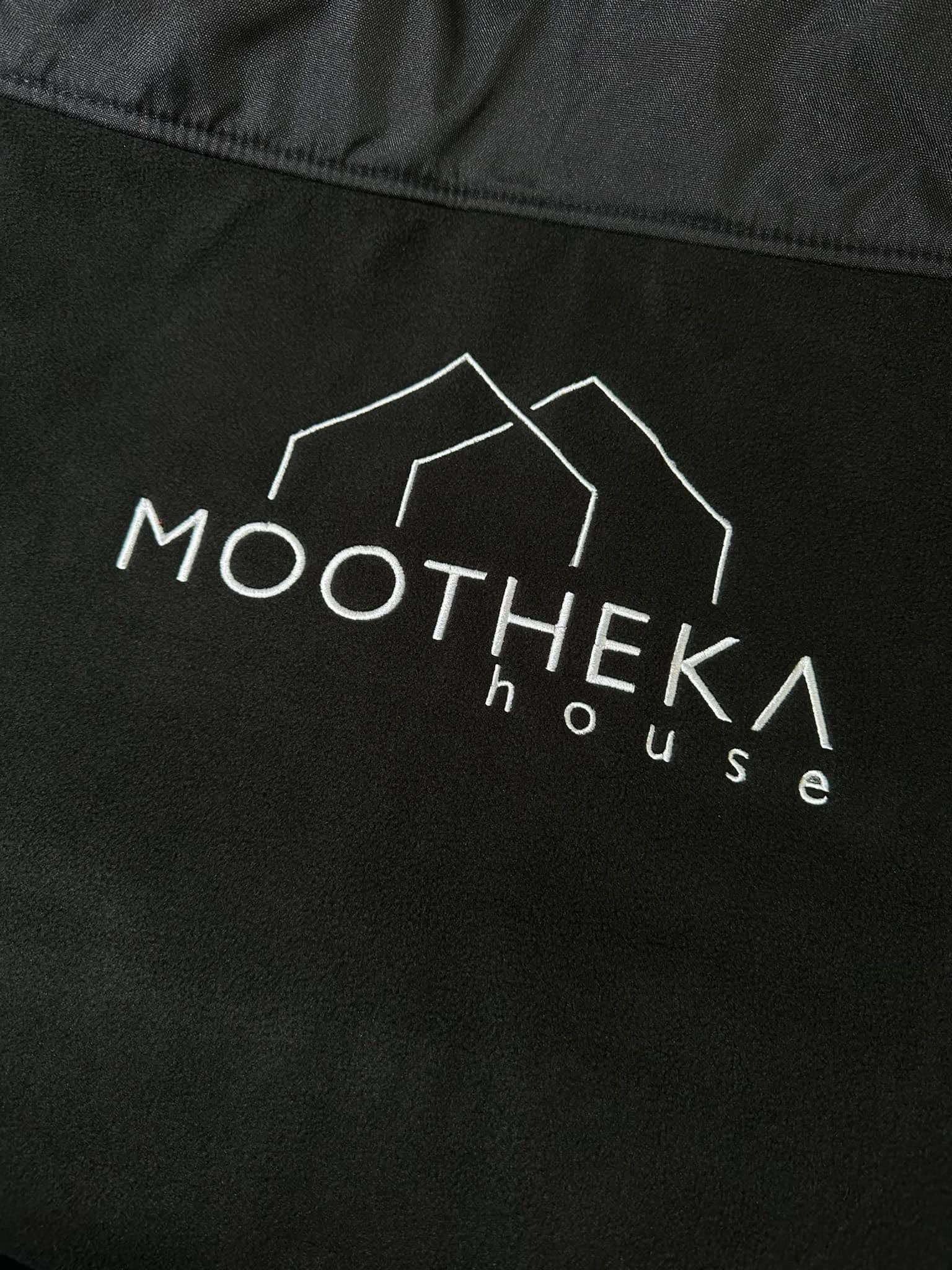 Czarna bluza z wyhaftowanym białym logo 'MOOTHEKA house' z abstrakcyjnym symbolem domu nad napisem.