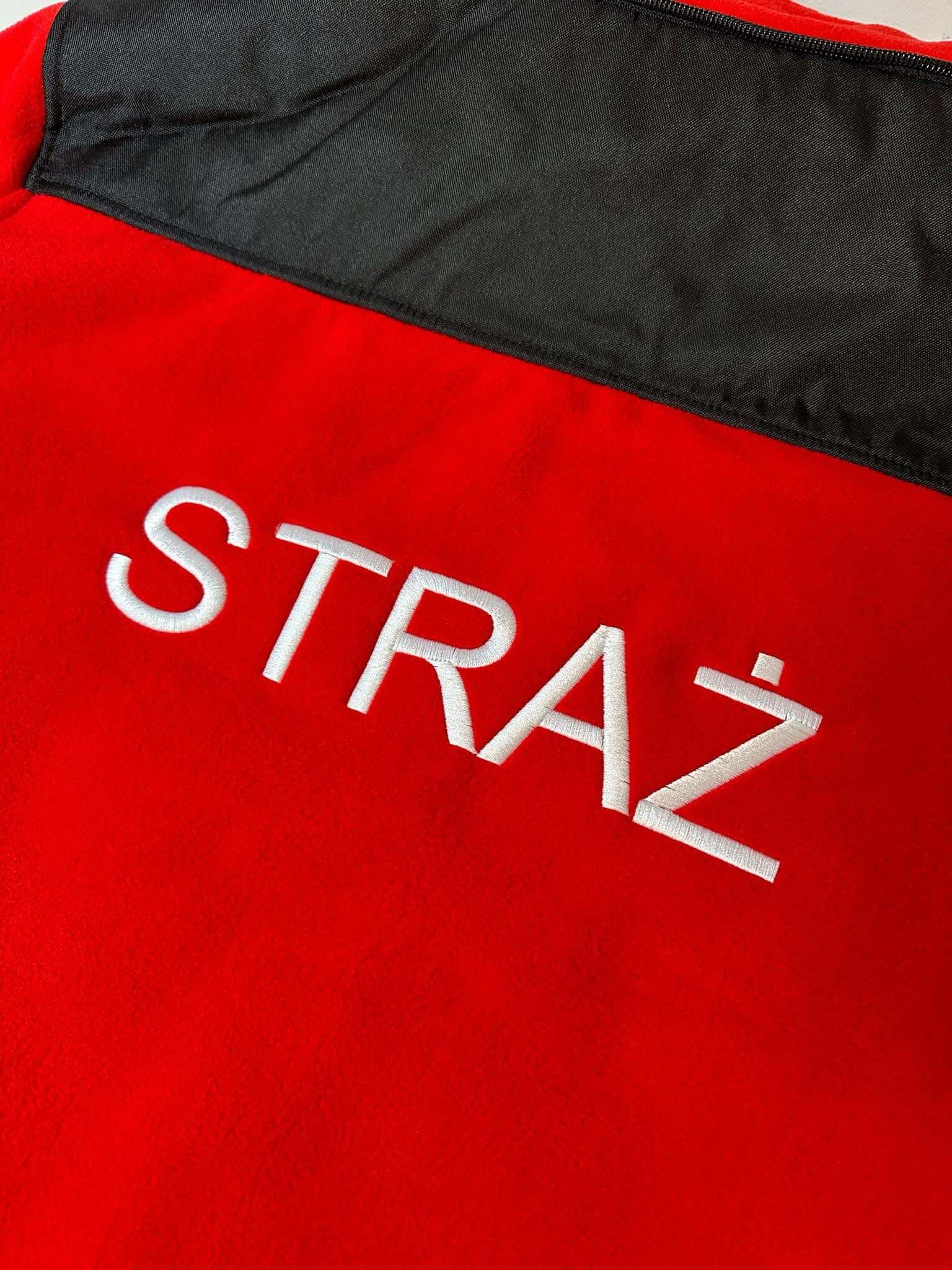 Czerwona bluza polarowa z czarnym karczkiem i białym haftowanym napisem 'STRAŻ'.