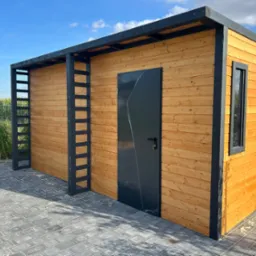 Nowoczesna, drewniana altana z czarnymi elementami konstrukcyjnymi, w tle widoczne pole kukurydzy.