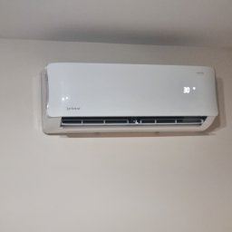 DM5 Daniel Mazuruk - Biała klimatyzacja Rotenso z wyświetlaczem 30 stopni Celsjusza, zamontowana na jasnej ścianie. Widok centralny, bez dodatkowych elementów.