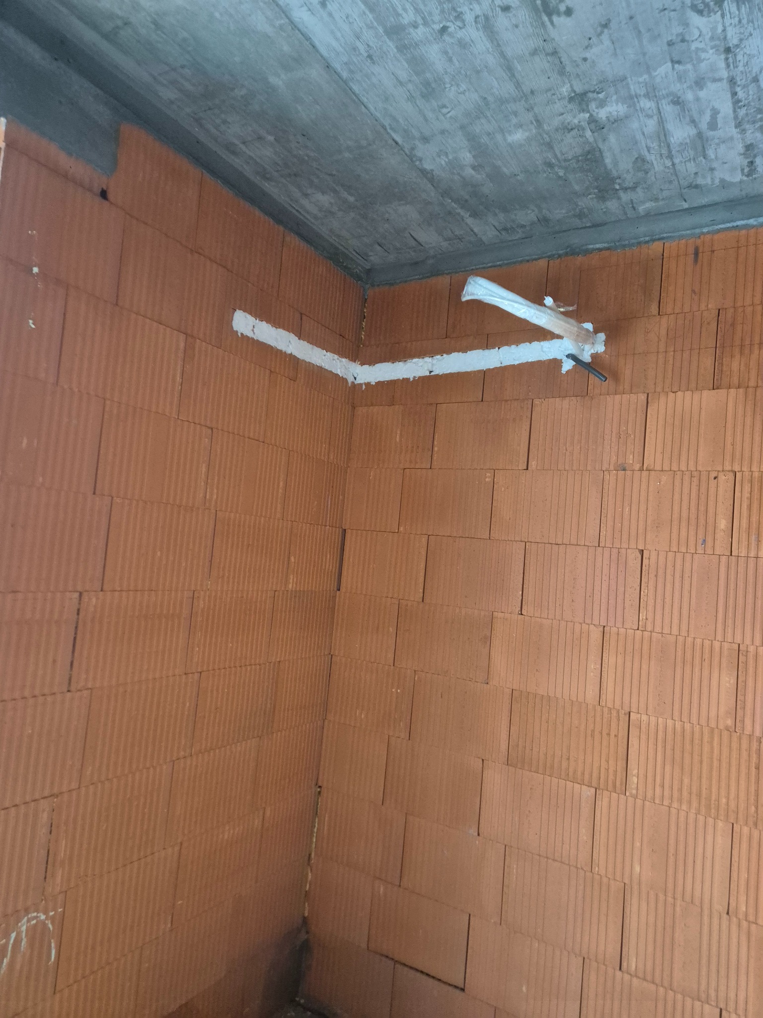 Wewnętrzny mur z pustaków z poprowadzoną instalacją klimatyzacji w Grabanowie. Rury zabezpieczone pianką montażową.