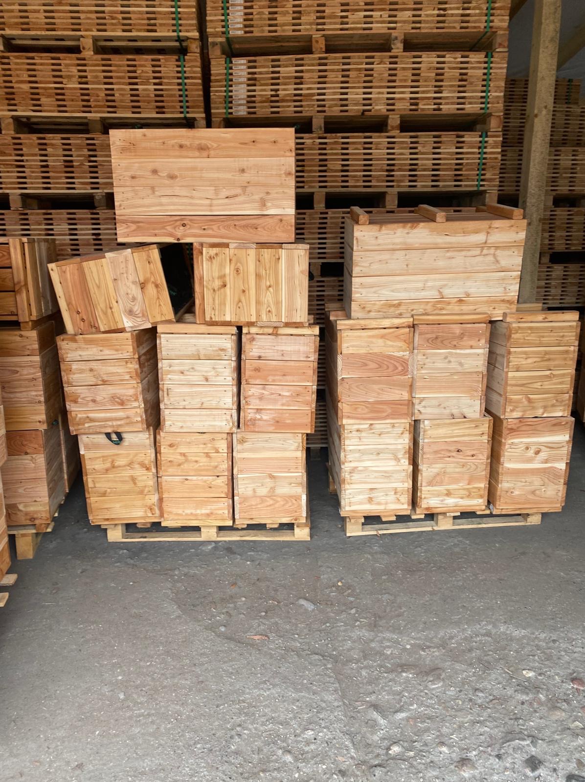 Magazyn pełen drewnianych skrzyń i palet, widoczne słoje drewna i surowa faktura materiału.