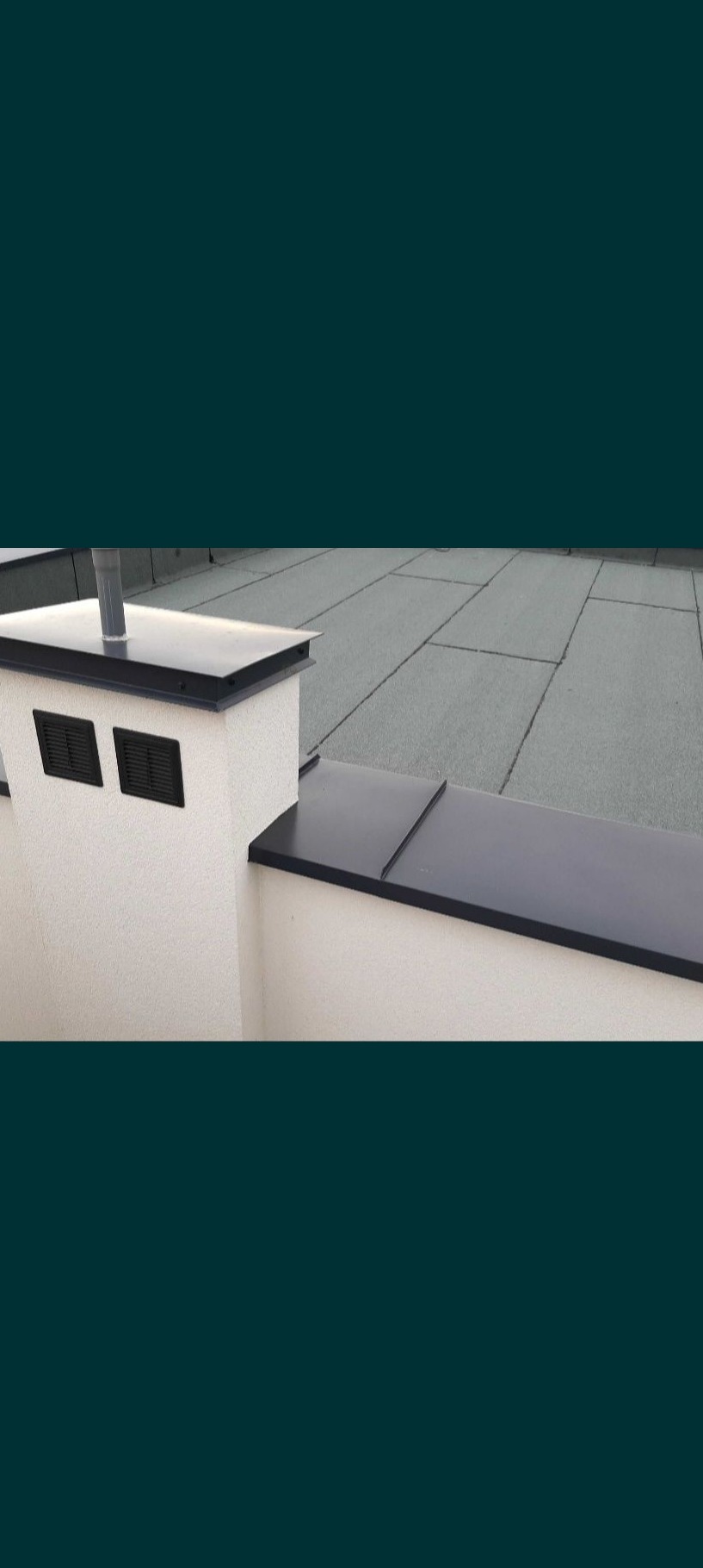 Szary dach pokryty papą termozgrzewalną, komin z wentylacją i obróbkami blacharskimi w kolorze czarnym.