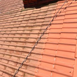 Firma Ogólnobudowlana Wiktor Marczak - Częściowo wyczyszczony dach z czerwonej dachówki. Po lewej stronie widać brudną, niezabezpieczoną część, a po prawej czystą, umytą część dachu.