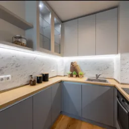 Szara kuchnia narożna z drewnianym blatem, marmurowym backsplashiem i oświetleniem LED pod szafkami, detale takie jak zioła w doniczkach i akcesoria kuchenne na blacie.