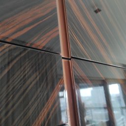 BEGI sp. z o.o. - Lakierowane fronty szafy z dekoracyjnym fornirem w odcieniach brązu i czerni, wykonane na wymiar w Zblewie. Widoczne detale łączeń i odbicie światła.