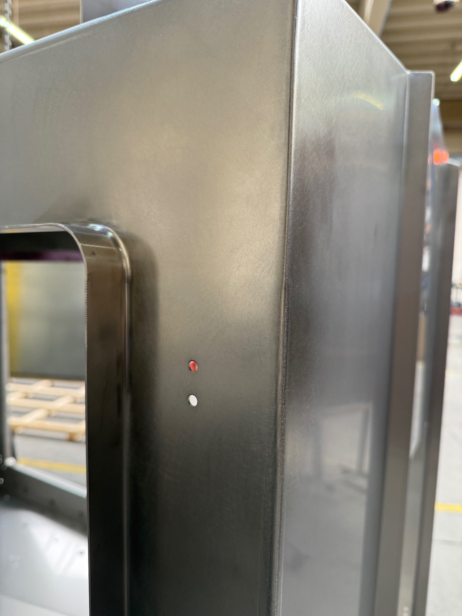 Szczegółowe ujęcie metalowej konstrukcji z widocznymi spawami i elementami montażowymi, prezentujące precyzję wykonania i jakość obróbki metalu w hali produkcyjnej.