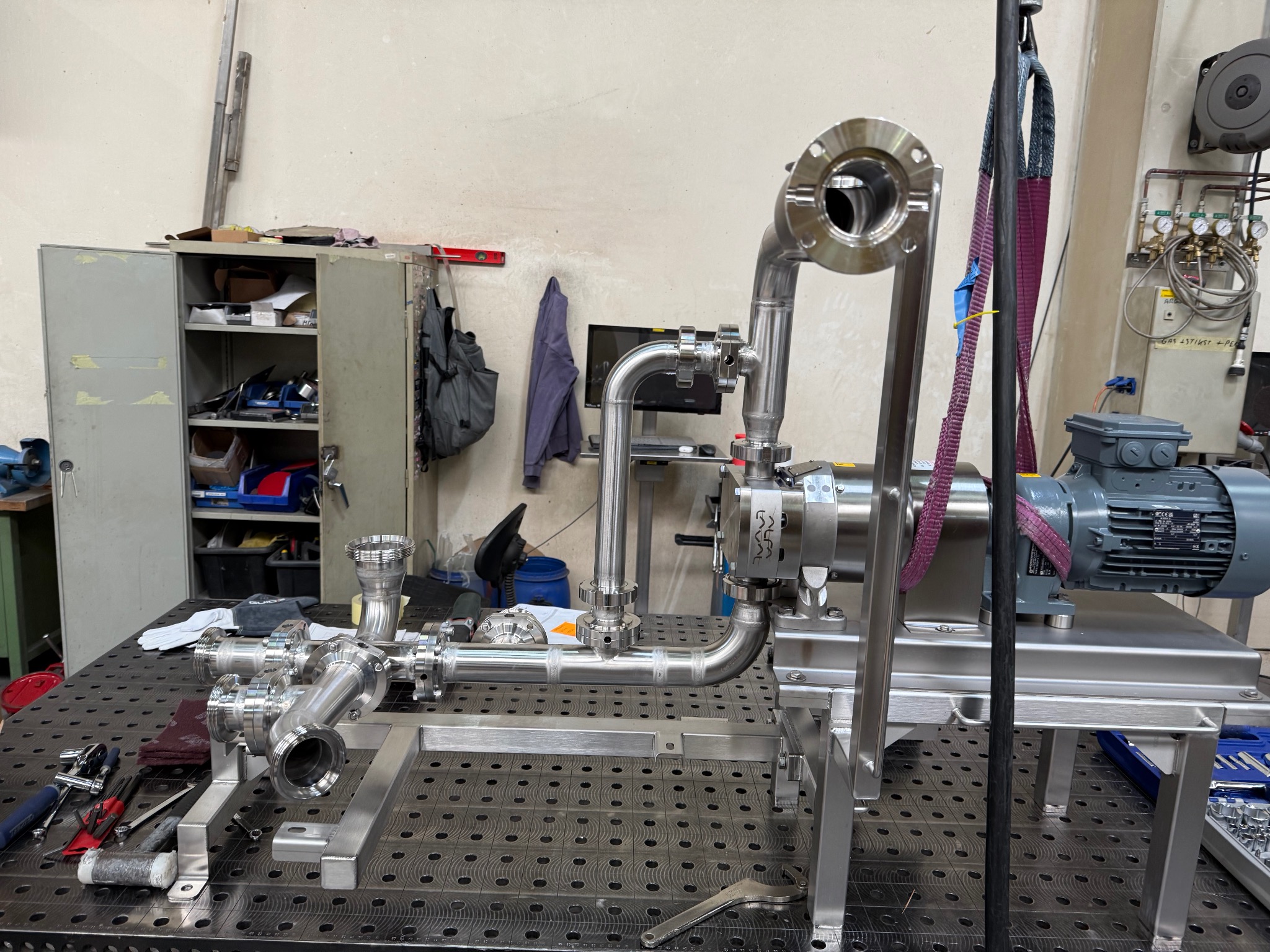 Precyzyjnie wykonana instalacja ze stali nierdzewnej na stole spawalniczym w Gdańsku. Widoczne liczne złącza i elementy, świadczące o skomplikowanym projekcie.